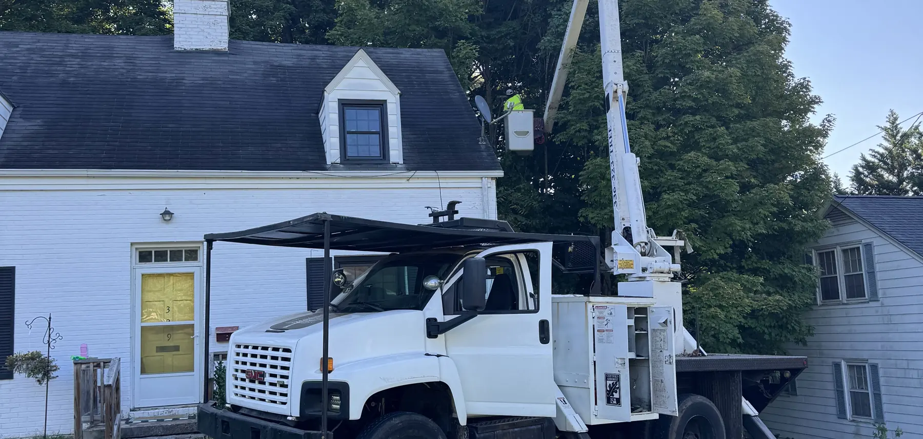 Prime Tree & Landscape bucket truck working a removal beside a house